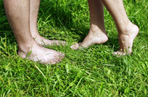 A man and woman's bare feet in the grass.
