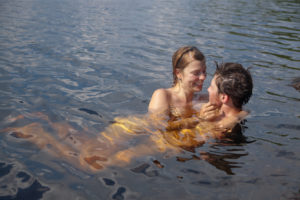 Loving, playful couple lounging together in the water of a lake