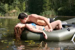 A man and woman lounging seductively in a blow up boat on a lake