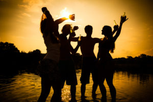 2 couples standing in water on a beach at dusk