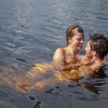 Loving, playful couple lounging together in the water of a lake